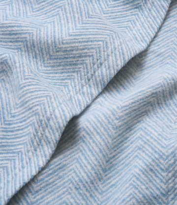 Light blue and white herringbone patterned woven shawl with draped folds showing fabric texture.7