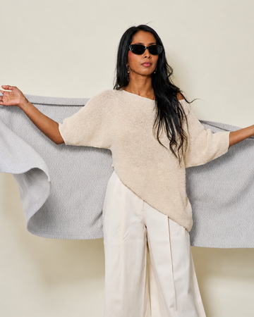 Light grey herringbone shawl with diagonal weave pattern, draped across shoulders and outstretched arms.3