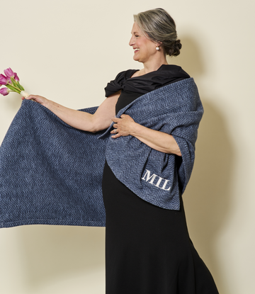 Midnight navy herringbone shawl with monogrammed corner worn over black dress by woman holding pink flowers.9