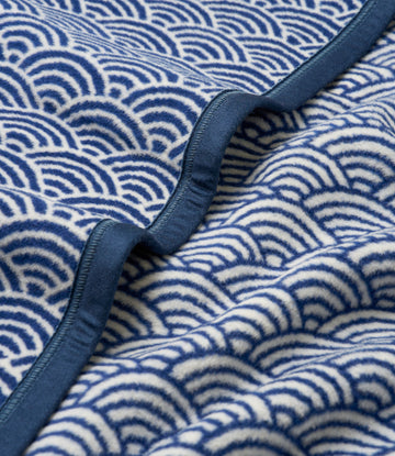 Blue and white scallop-patterned blanket with navy binding detail along the edge.6