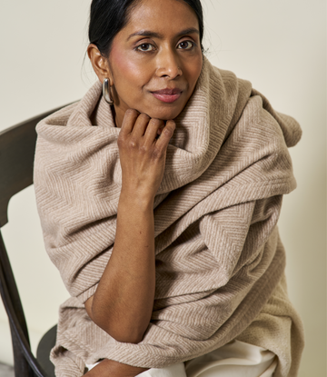 Woman wearing a wheat-colored shawl with herringbone texture draped around shoulders.3