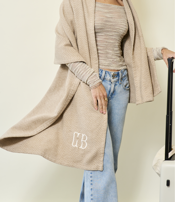 Beige herringbone shawl with monogram draped over model wearing striped top and light wash jeans.9