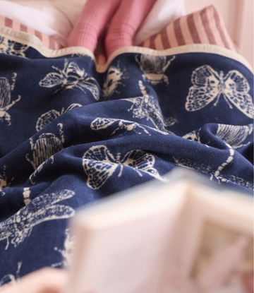Navy blue blanket with cream insect print, striped pink and cream trim on edges.4