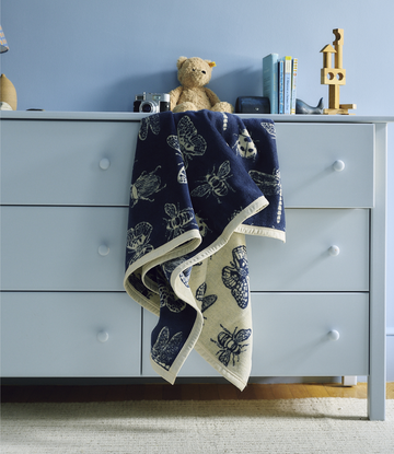 Navy and cream blanket with black bug print, draped over white dresser with cream binding.3