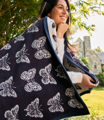 Navy and cream blanket with butterfly pattern and blue trim, worn over shoulders outdoors.2