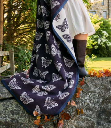 Navy and cream blanket with white butterfly print and blue binding, draped outdoors.3
