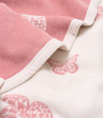Pink and white blanket with embroidered butterfly details and white binding edges.4