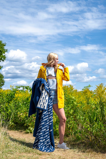 Navy blue blanket with white fish pattern draped over woman's shoulder in outdoor setting.4
