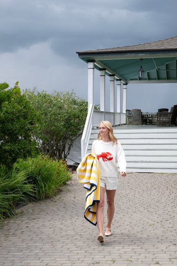 Yellow, white, and navy striped blanket draped over a woman's arm outdoors.4