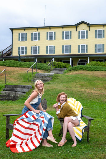 Red and white striped blanket draped over woman's lap on wooden chair outdoors.4
