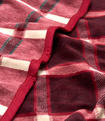 Red and cream plaid blanket with gray accents and red binding edge, showing textured woven fabric.8