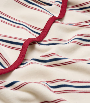 Cream blanket with red and navy horizontal stripes and a burgundy binding edge.6
