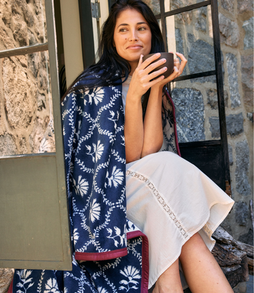 Navy blanket with white floral and geometric trellis pattern draped over woman's shoulders.3
