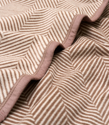 Beige and cream herringbone patterned blanket with woven striped texture and finished edge binding.2