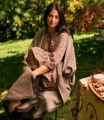 Brown herringbone blanket draped over a woman's lap in an outdoor garden setting.3