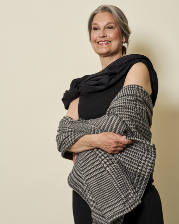 Woman wearing a gray and white houndstooth plaid shawl draped over her shoulders with a black sleeveless top.3