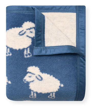 Blue mini blanket with white sheep pattern and cream fleece reverse side, shown folded with corner folded back.5