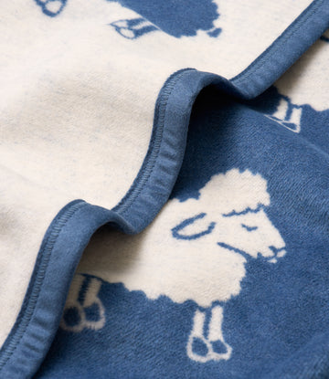 Blue and white blanket with lamb print pattern and bound edge detail.4