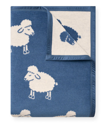 Blue and cream blanket with knit sheep and cloud pattern, folded to show reversible design with rocket motif.5