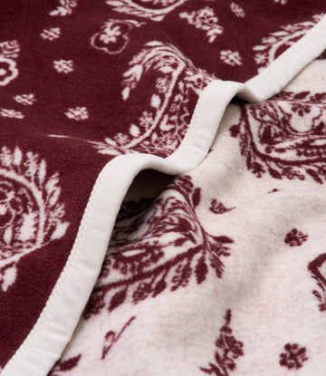 Burgundy and cream blanket with paisley pattern and white binding, shown folded to display both sides.7