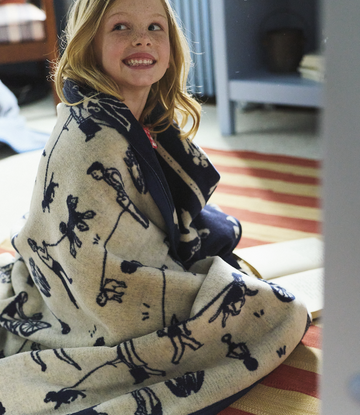 Child wrapped in cream-colored blanket with navy dog silhouette pattern throughout.2