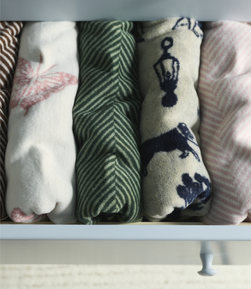 Four folded blankets with dog patterns including pink paw prints, green herringbone, navy dog silhouettes, and pink stripes.4