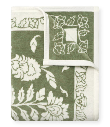 Folded blanket with green and cream tree and leaf pattern, white reverse side visible.6