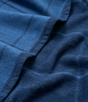 Navy blue blanket with windowpane plaid pattern and stitched detailing, showing soft fabric folds.6