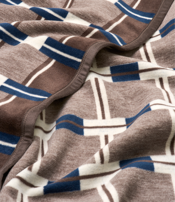 Beige knit blanket with geometric grid pattern in navy blue, brown, and cream stripes.5